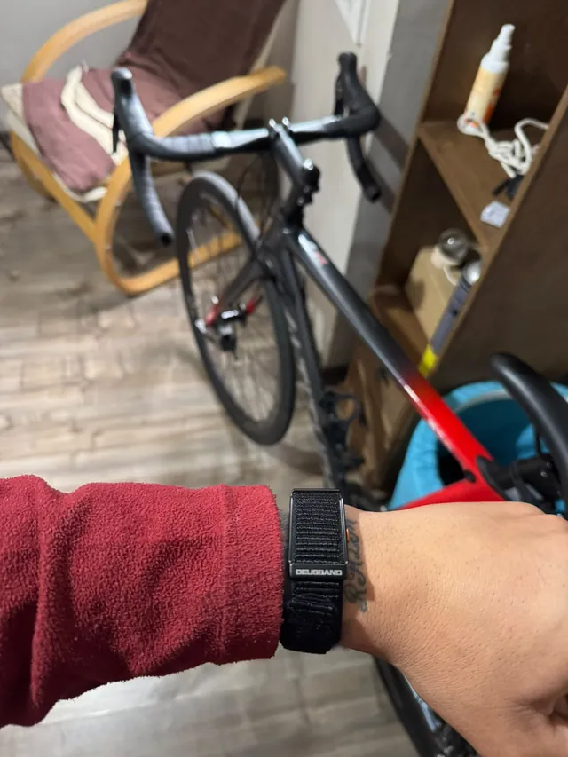 DEUS Band con correa de nylon en la muñeca, junto a una bicicleta de ruta — reseña de @martinnoct