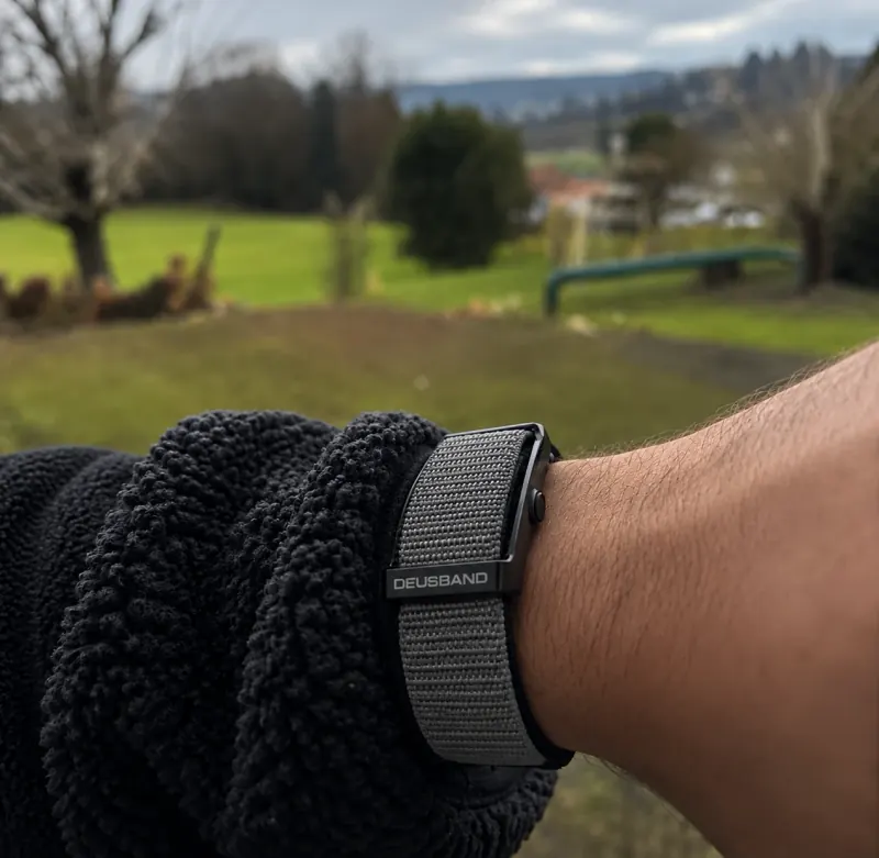 DEUS Band con correa de nylon gris en la muñeca al aire libre. Foto del cliente editada para mostrar la correa gris